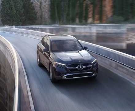 Dynasmic front 3/4 shot of a black 2025 Mercedes-Benz GLC driving over a bridge.
