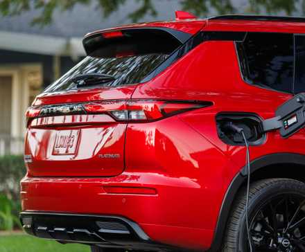 Red 2026 Nissan Rogue Plug-in Hybrid rear profile with charging cable