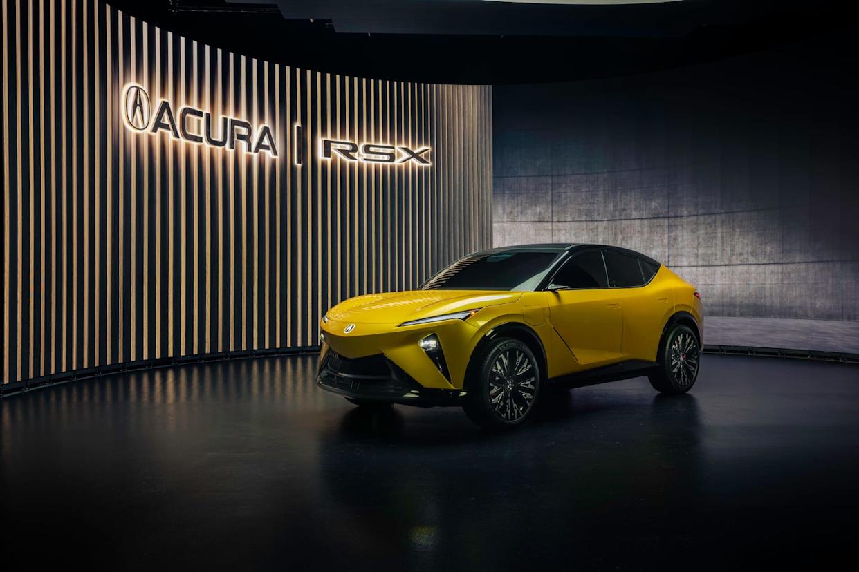 front three quarter view of yellow suv with black roof, vertical headlights, and closed grille on dark showroom floor.