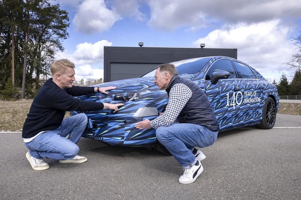 Mercedes ride engineer Ewald Dirks crouches at the front of the C-Class Electric prototype with Greg Kable
