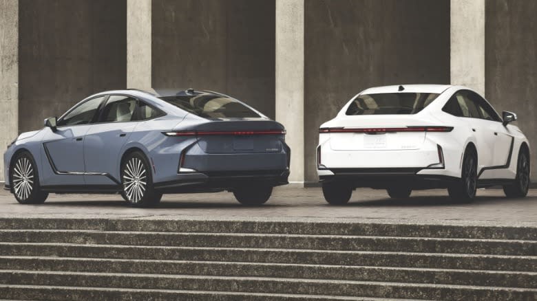 A photo of the rear of a gray-blue ES and a white one parked at the top of a staircase in front of concrete pillars