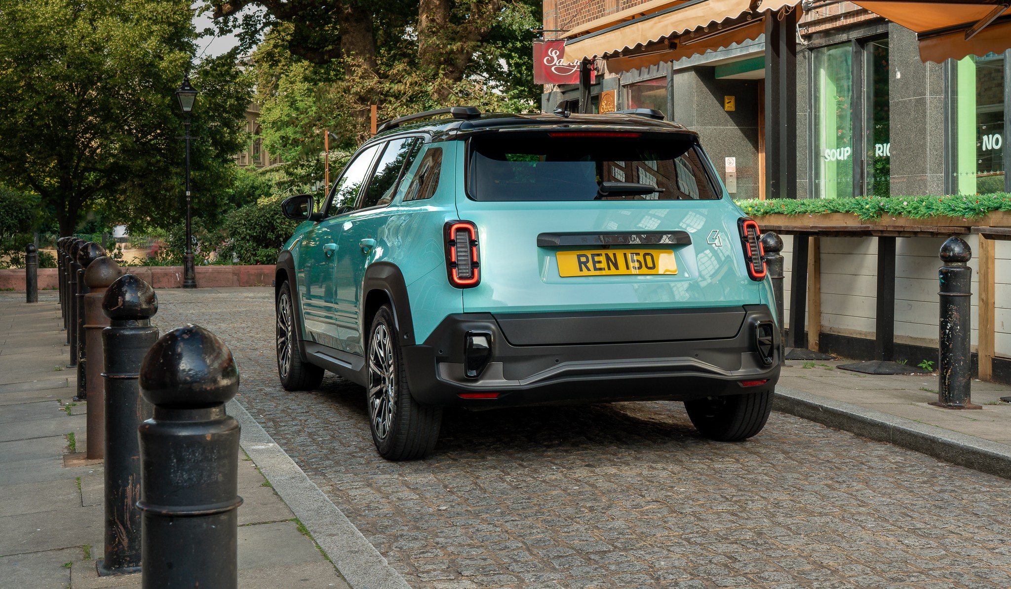 Rear view of a 2025 Renault 4 E-Tech parked on a cobblestone street.