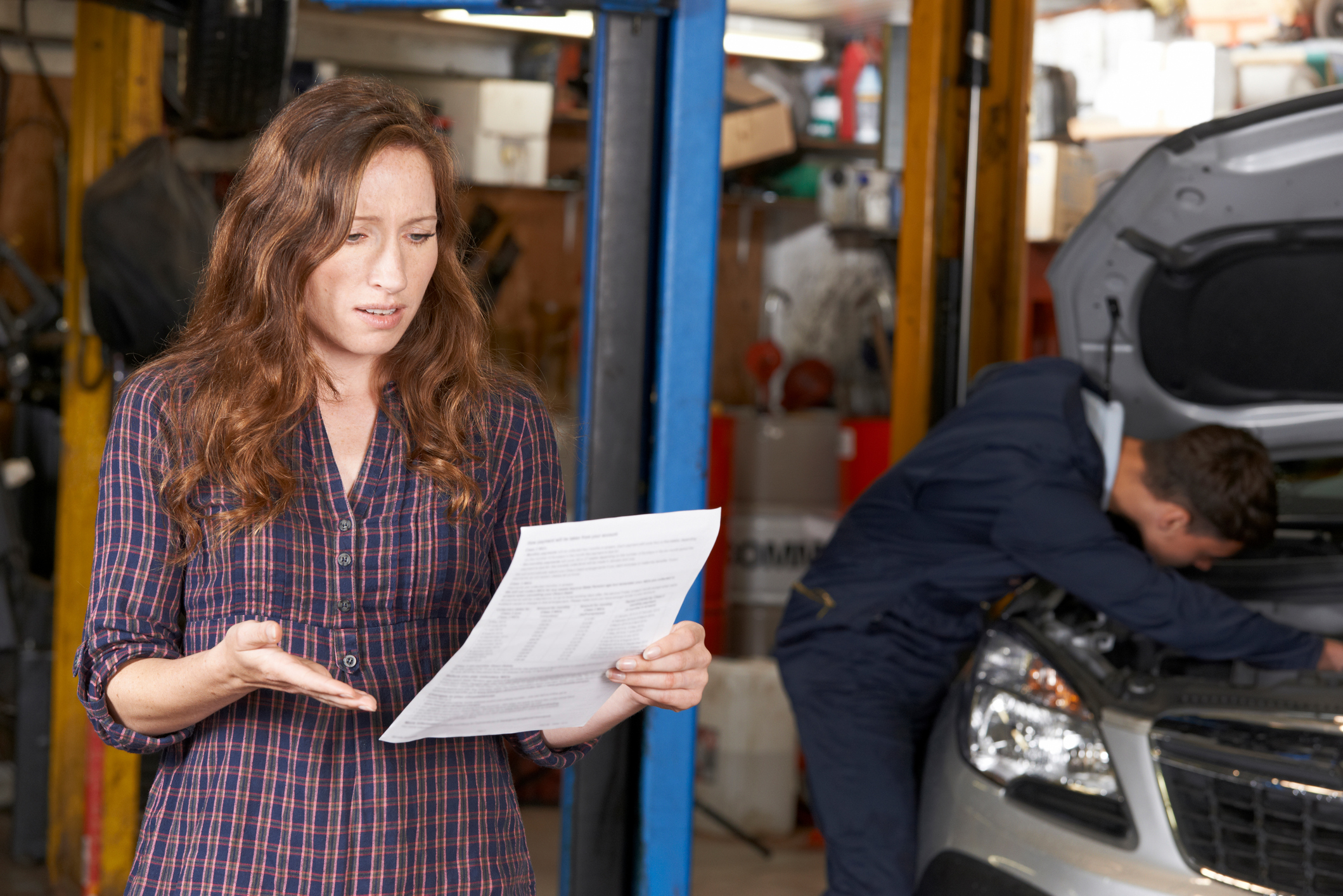 a woman shocked as she reads her car repair bill