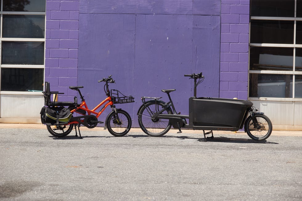 Two bicycles parked in front of a purple wall.