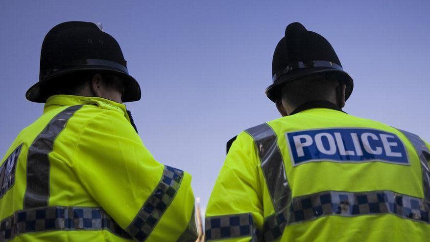 A close-up of the back of two police officers in high-vis jackets