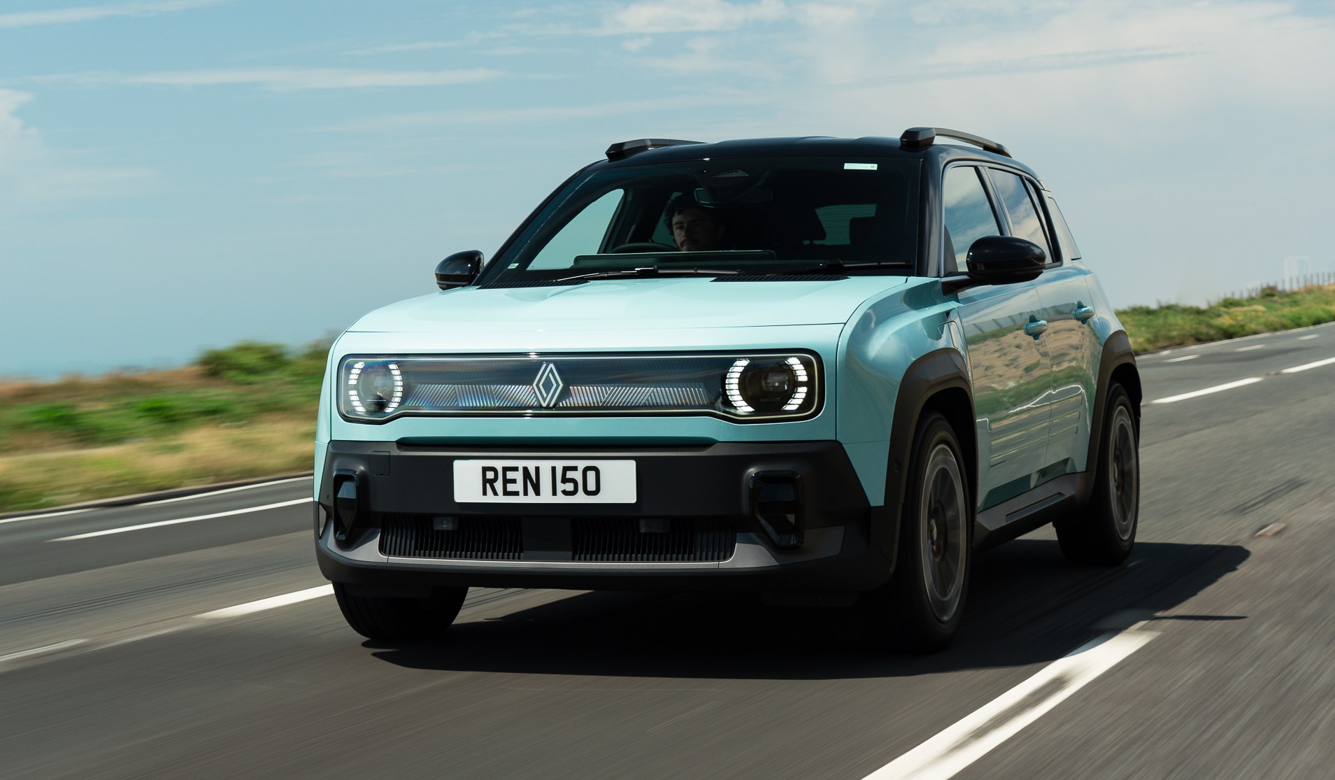 Light blue 2025 Renault 4 E-Tech driving on a road.