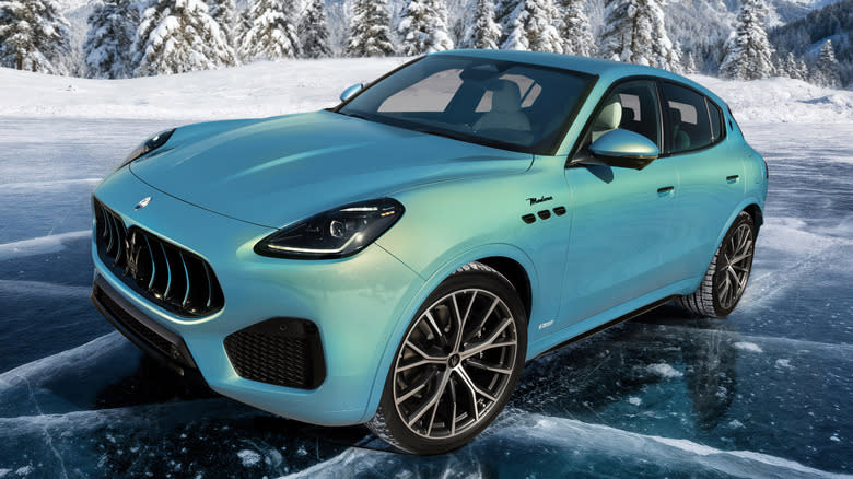 A turquoise pearlescent Maserati Grecale Folgore parked on ice with snow and a mountaintop in the background.
