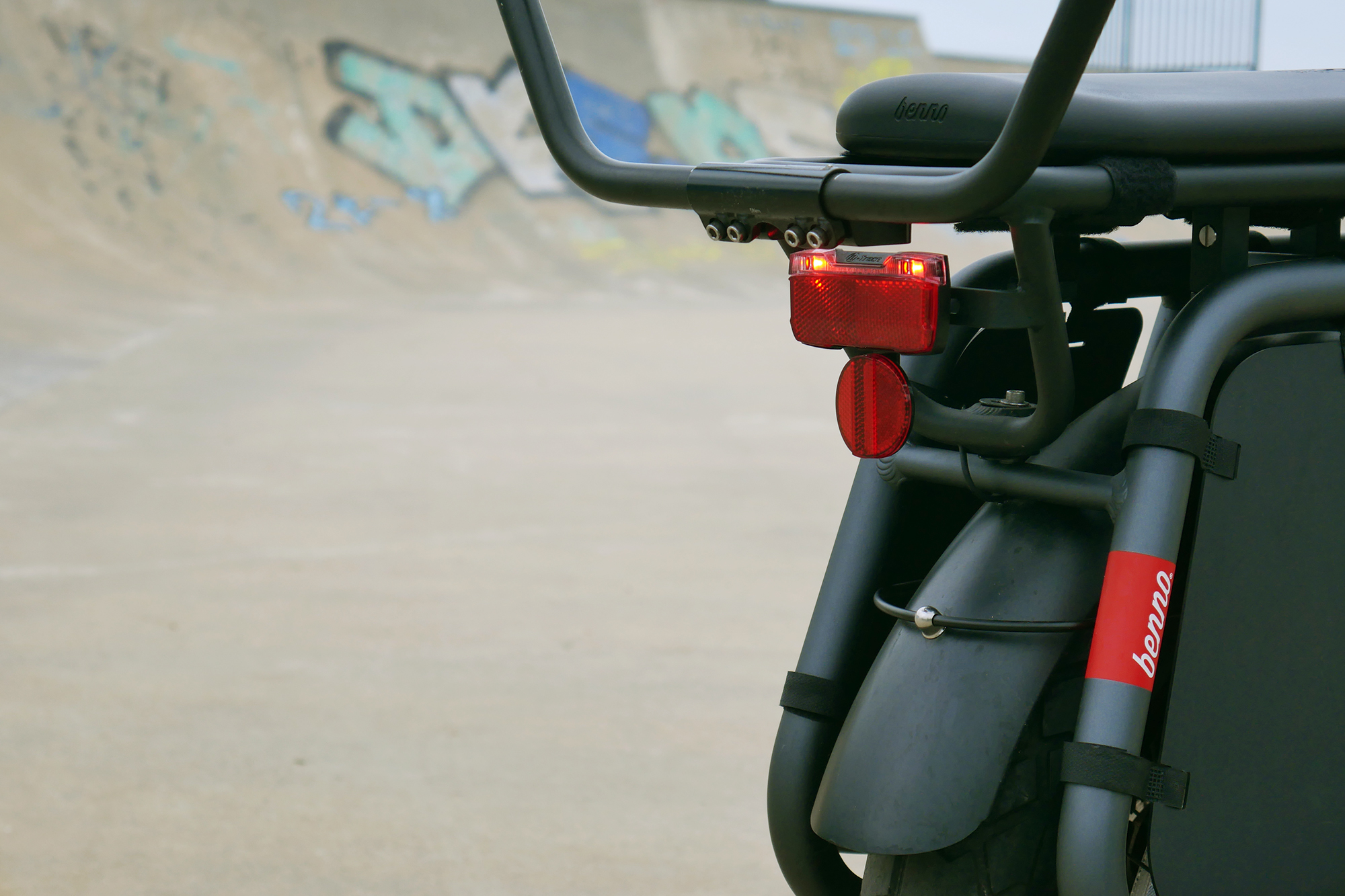 Red rear light eluminated on the Benno RemiDemi XL against the backdrop of a concrete skatepark