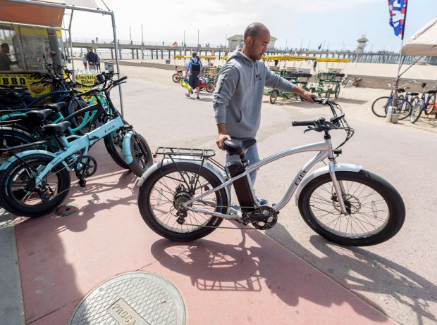 Joseph Ali readies electric bicycles at his shop, Zach's Beach Rentals, near the pier in Huntington Beach in April 2021. Ali said e-bikes make up about half of his bike rental sales. (Photo by Paul Bersebach, Orange County Register/SCNG)