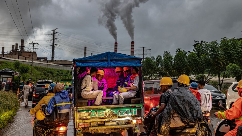 Nickel industry workers rides a modified mini pick-up used as a local public transport in Halmahera island, North Maluku, Indonesia, amidst local traffic congestion and smoldering chimneys of nickel smelting and processing plant, August 2024. (CGSP / Mas Agung Wilis Yudha Baskoro)