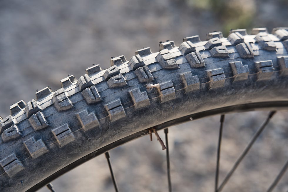 Close-up of a mountain bike tire tread showing wear and dirt.