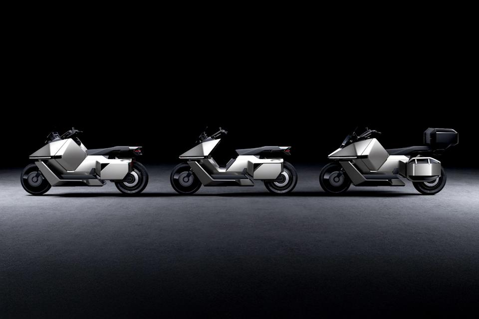 Three silver futuristic electric motorcycles with angular designs and black seats lined up on a dark floor against a black background.