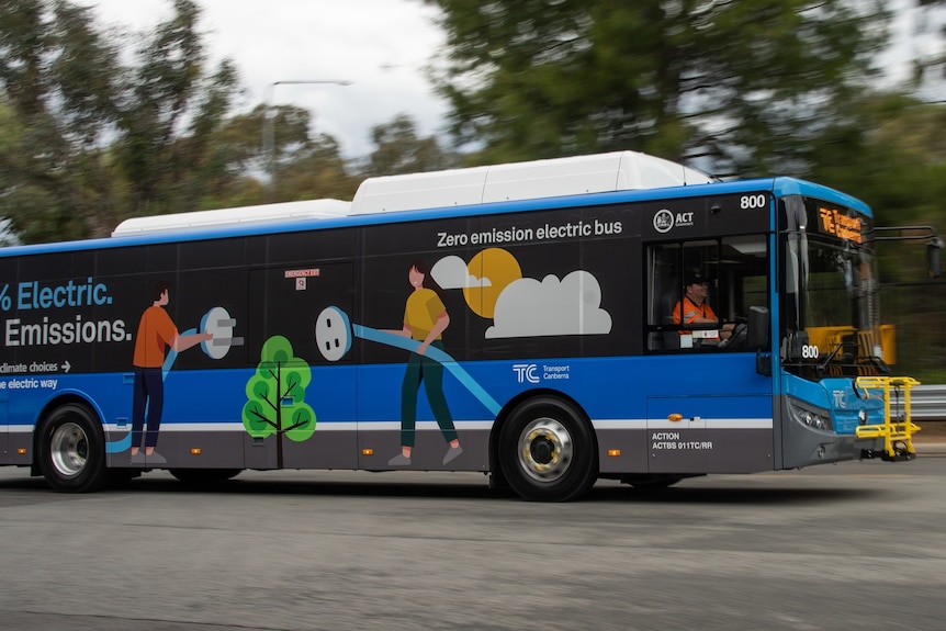 A blue electric bus driving along a road. 