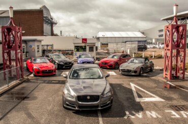 Six Jaguar cars on display in a parking lot at the Castle Bromwich factory.