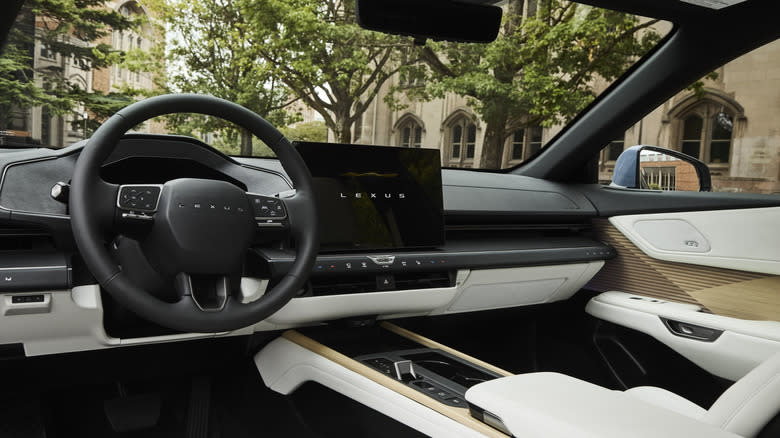 A look at the dashboard of the 2026 Lexus ES with a white and black color scheme, wood on the doors, and trees and buildings out the windows
