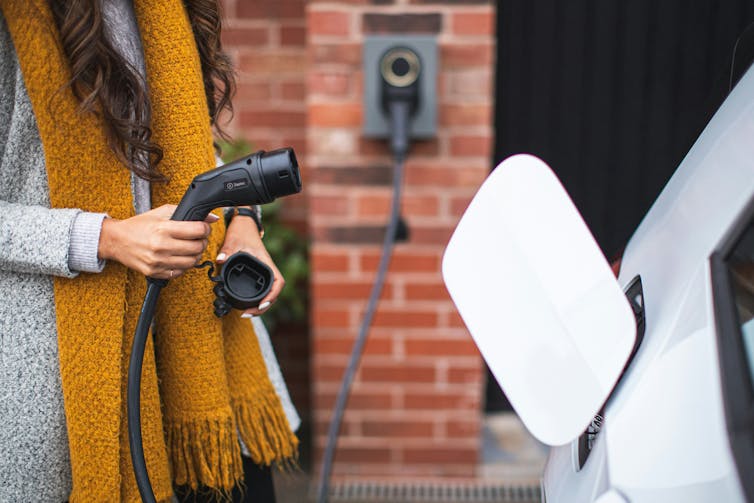 A woman in a yellow scarf prepares to plug in her charger.