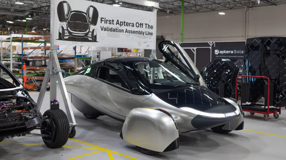 first aptera vehicle on the assembly line with a sign overhead