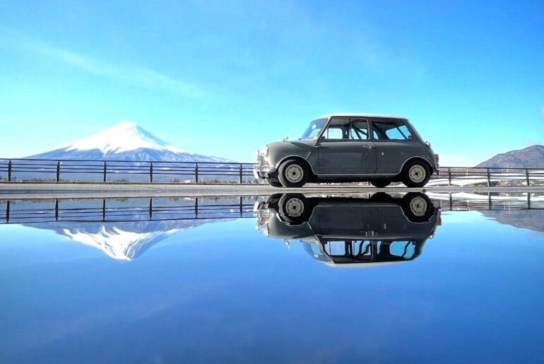 This image shows a classic 1960s *Morris Mini Cooper Mk I*, with Mount Fuji in the background 🇬🇧 🇯🇵