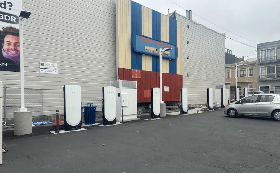 Tesla Supercharger station in front of a building with a "Hotel Miraloma" sign.