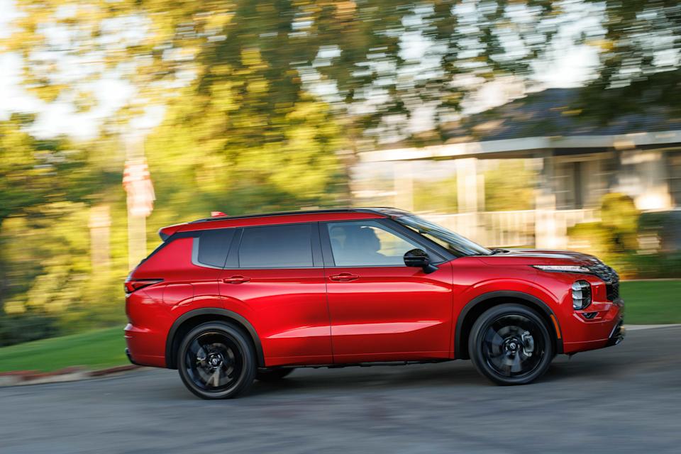 Red 2026 Nissan Rogue Plug-in Hybrid driving through a neighborhood. 