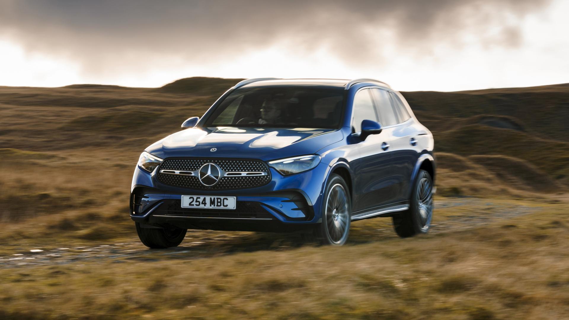 A blue Mercedes-Benz GLC driving on a grassy track.