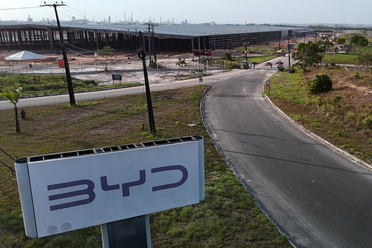 A factory under construction in the distance, with a large BYD sign in the foreground.
