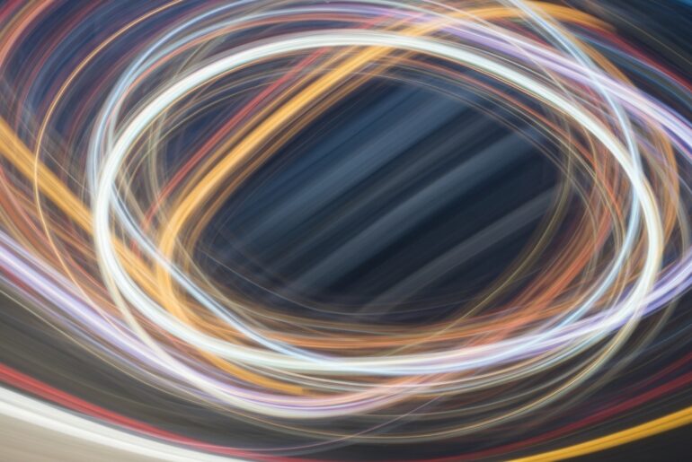 An abstract, colorful image featuring sweeping, blurred lines that represent the movement of a hybrid vehicle, conveying a sense of speed and modern engineering.