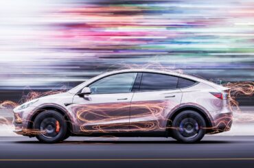 An abstract, blurred image of a Tesla electric vehicle in motion, with vibrant streaks of color and a sense of speed and modern engineering.