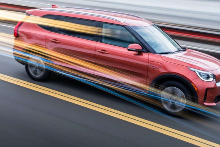 An abstract, blurred image of a Kia PV5 electric van in motion, with vibrant streaks of color representing its speed and modern engineering.