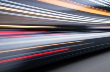 An abstract, colorful image of a moving electric vehicle, with blurred lines and shapes conveying a sense of speed and modern engineering.