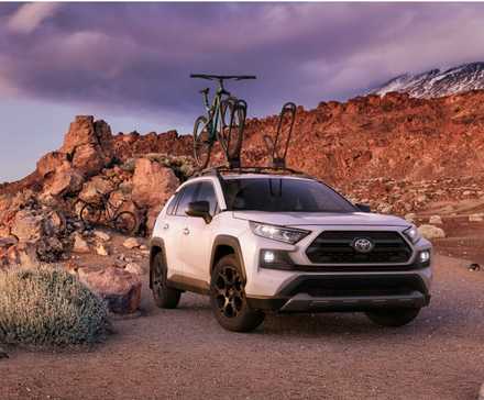 White 2020 Toyota RAV4 off-roading with a bicycle on its roof.