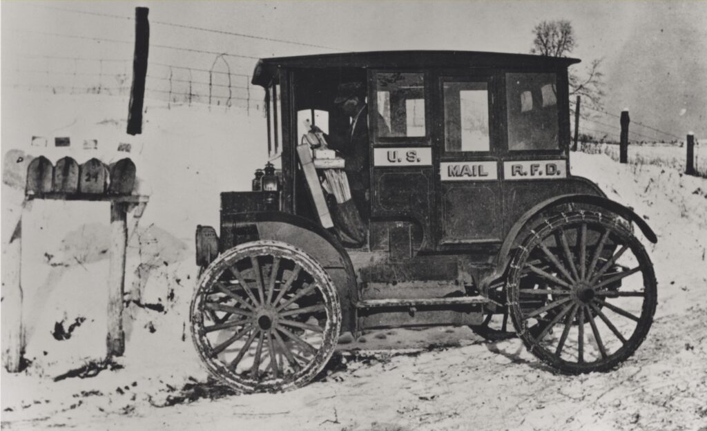 Photograph of rural carrier in automobile at mailboxes, 1910