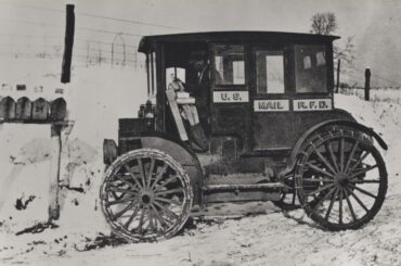 Photograph of rural carrier in automobile at mailboxes, 1910