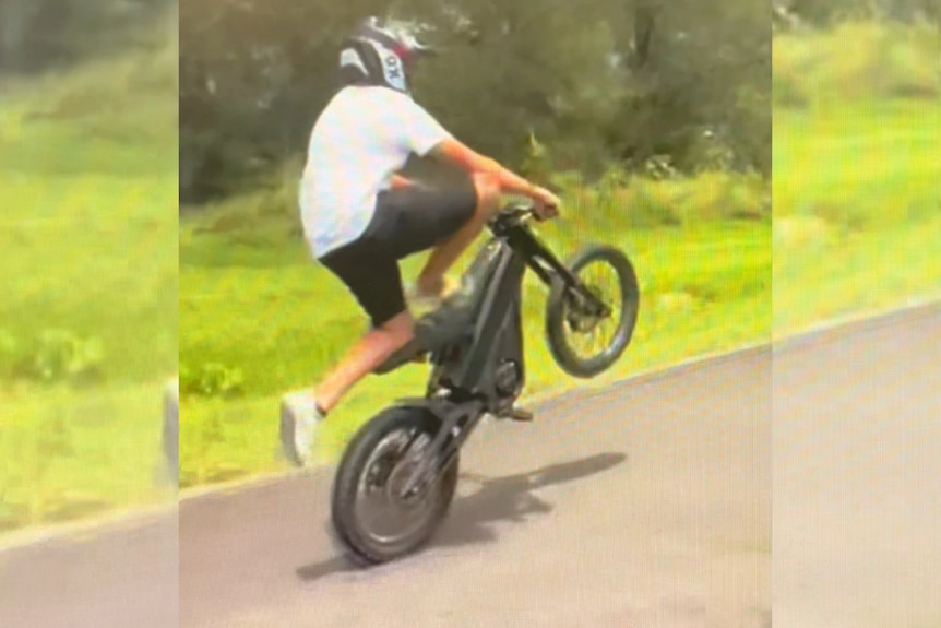 A person on an electric motorbike doing a wheelie
