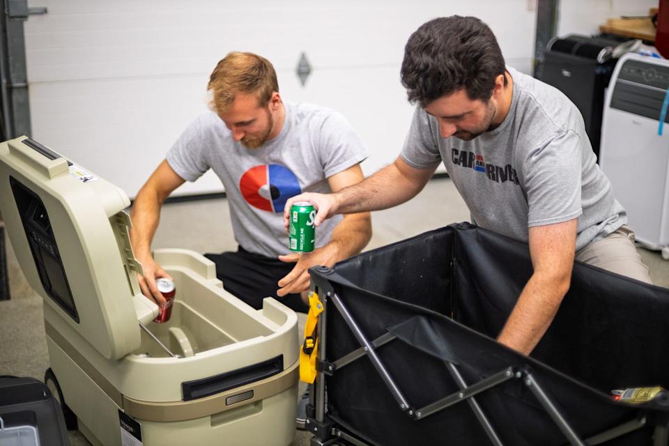 two men handing cans over to put into a cooler