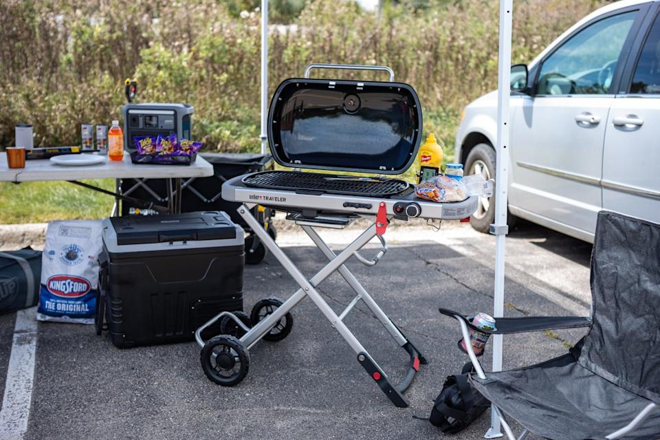 a grill with food on it amongst a tailgating setup