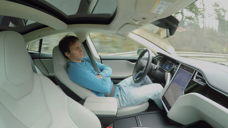 Man closes his eyes behind the wheel of a Tesla