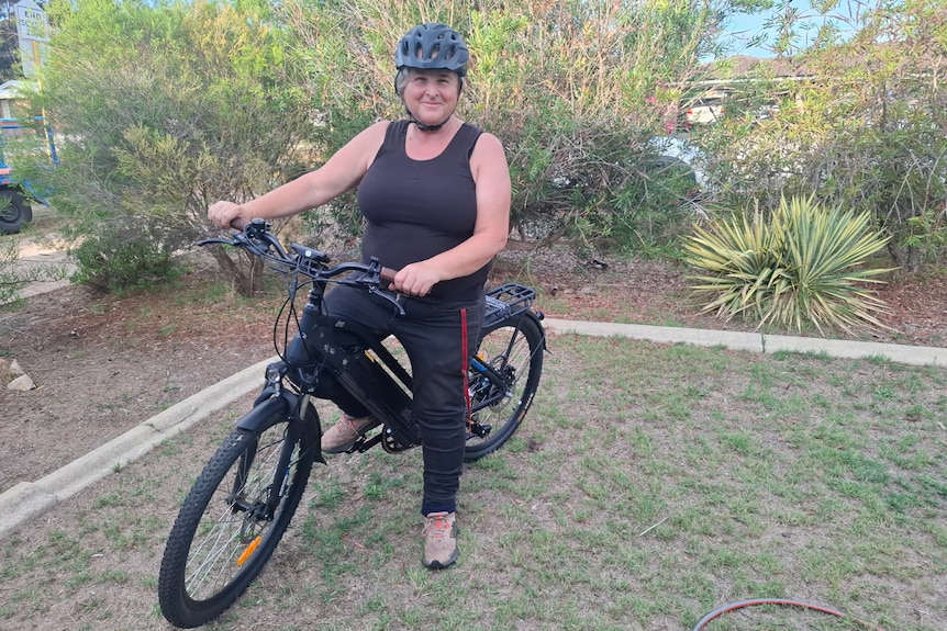 A woman with a black tank top rides an e-bike