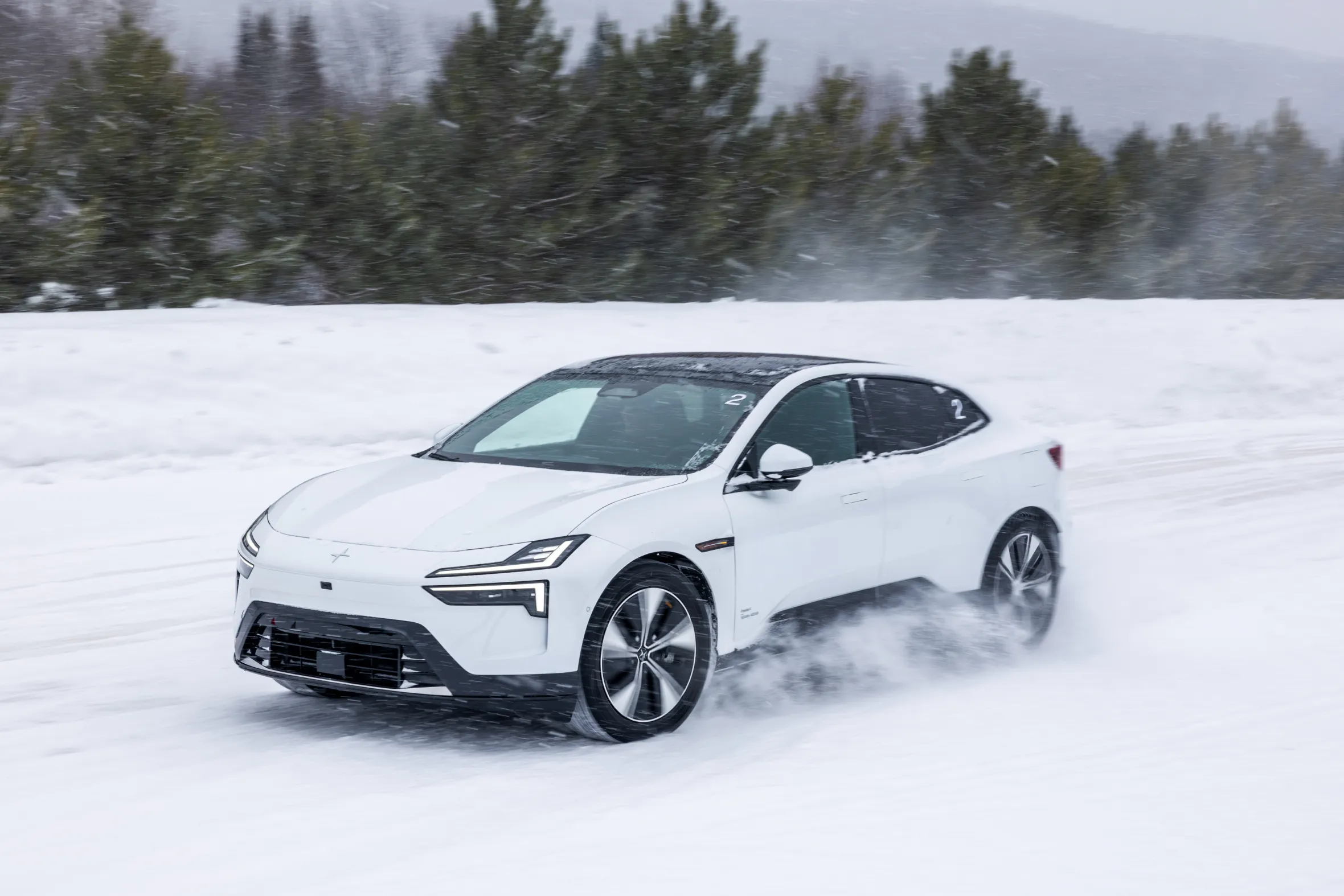 White Polestar 4 electric vehicle driving through snow.