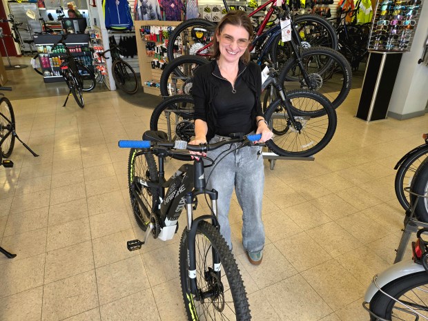Viola Luba of St. Charles stands by the e-bike she bought recently at The Bike Rack in St. Charles. (David Sharos/For The Beacon-News)