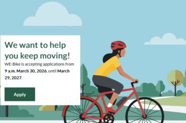 Illustration of a person riding an e-bike on a tree-lined path. Text: We want to help you keep moving! WE-Bike is accepting applications from 9 am March 30, 2026 until March 29, 2027.