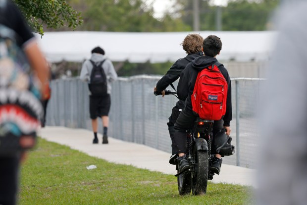 Helmetless e-bike riders enter Rickards Middle School in Oakland Park on Wednesday, April 1, 2026. (Amy Beth Bennett/South Florida Sun Sentinel)