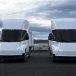 Two design-refreshed Tesla Semi trucks parked in the open at Giga Nevada.