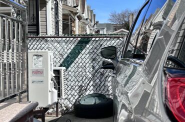 Electric car parked in driveway plugged in and charging with Fujitsu charging station