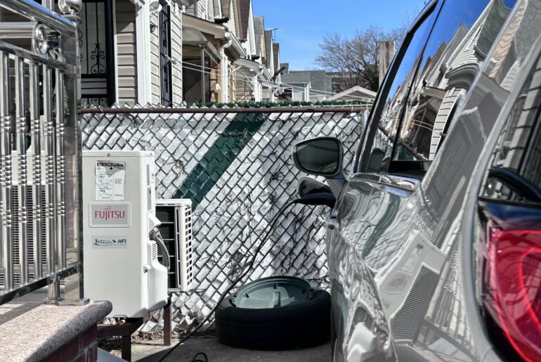 Electric car parked in driveway plugged in and charging with Fujitsu charging station