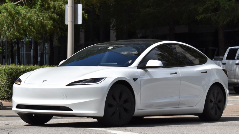 a white Tesla EV driving down the street