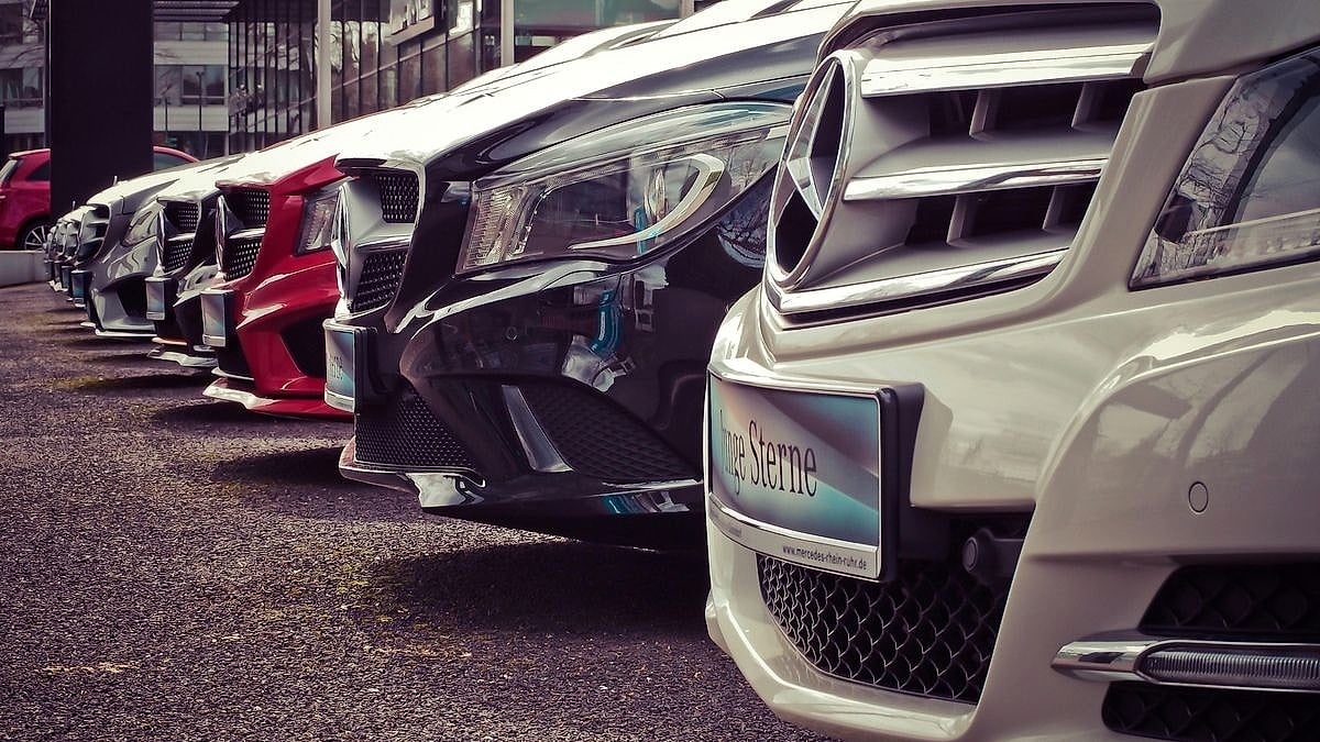 Row of Mercedes-Benz vehicles lined up at a dealership lot with Junge Sterne dealer plate on white model in foreground