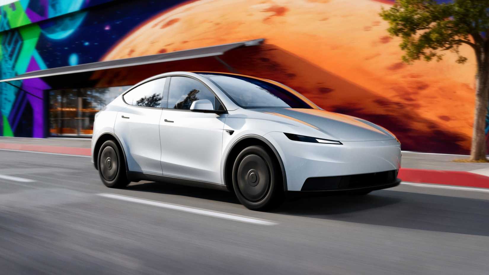 A white Tesla Model Y Standard driving on a street