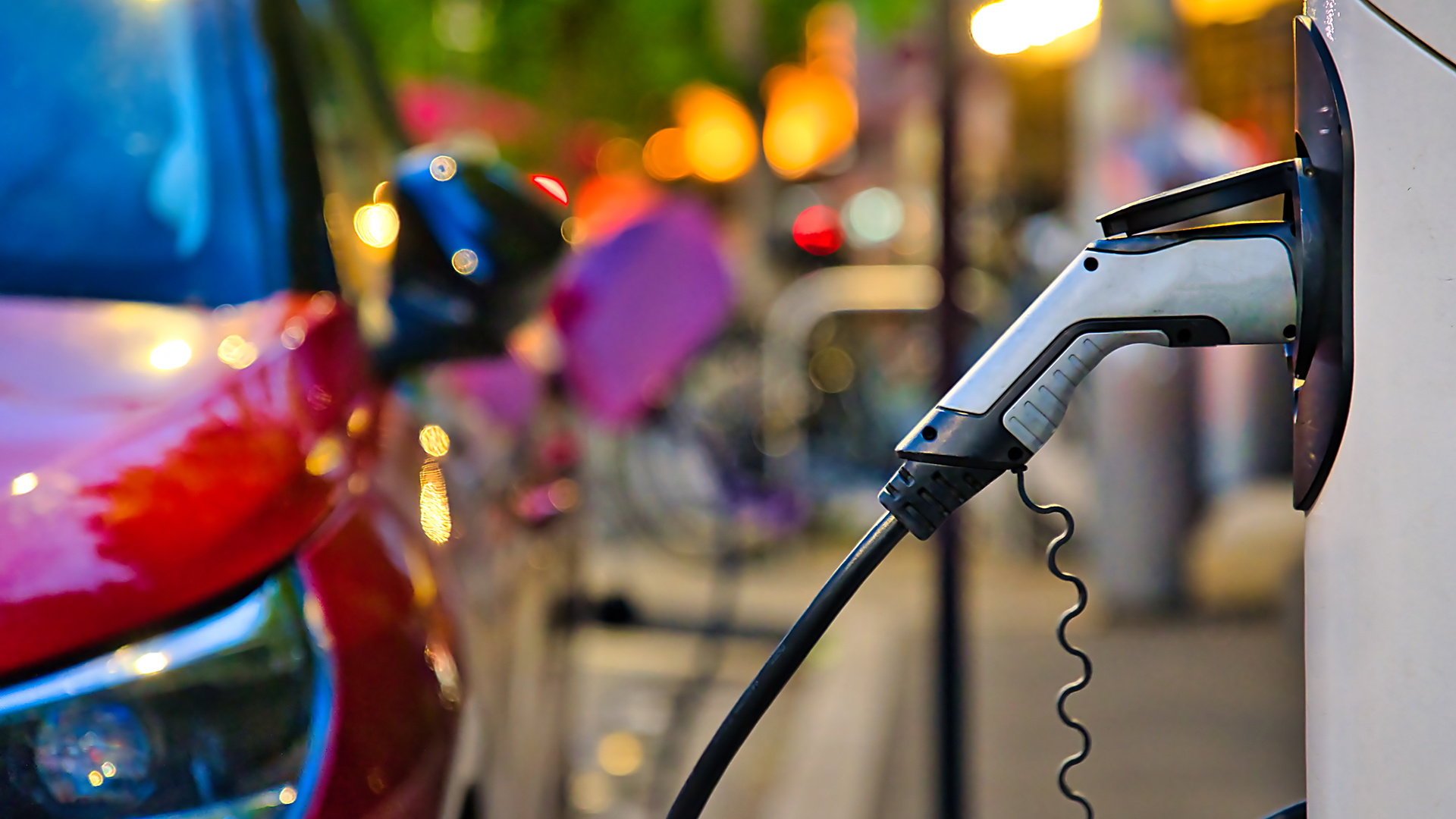 EV charger with red electric car in background