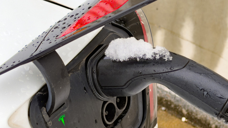 Snow on top of a EV battery charger plugged into an EV